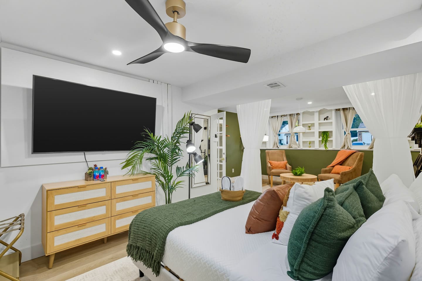 The Green Hideaway room is a bright, cozy space with soft green accents, a comfy daybed, and plenty of natural light. Simple décor and plants make it a peaceful spot to unwind.