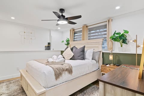 The Iris room features soft green tones, warm wood accents, and a cozy queen bed for a calm, relaxing stay.