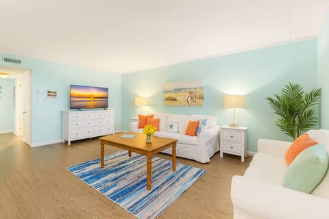 Step into comfort at OC Oasis — our bright, beach-inspired living room features plush couches, a large smart TV, and plenty of space to unwind after a day exploring Ocean City.
