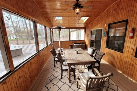 Enjoy your morning coffee or evening meals in this spacious, screened-in porch! You'll love the warm wood ambiance, cozy seating, & ceiling fan for comfort, all with scenic views. Perfect for relaxing!