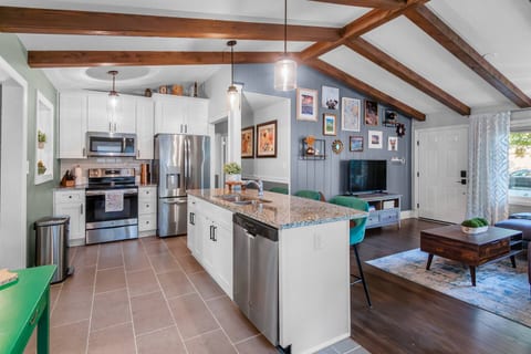 Enjoy cooking in this modern kitchen with stainless steel appliances, including a fridge with water & ice dispenser and an electric stove. The open layout with vaulted ceilings, granite island, and cozy living area makes it perfect for entertaining.