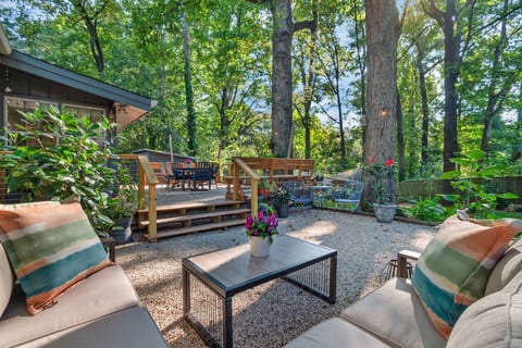 Seamless flow from the cozy gravel patio lounge to the elevated deck with dining space. Ideal for indoor-outdoor entertaining under the shade of mature trees.