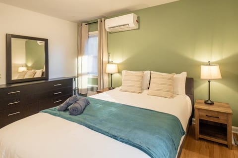 Calming bedroom with green and beige décor, twin bed, bedside lamps, chandelier, and window light.
