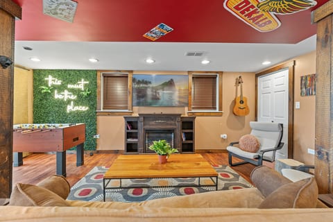 Cozy game lounge with foosball, fireplace, neon vibe, and comfy seating