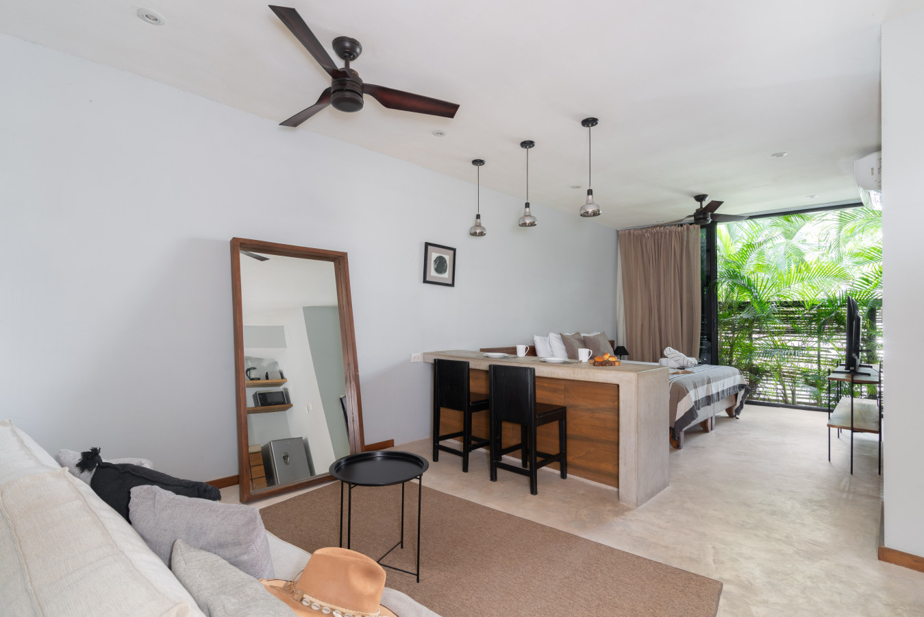 Stylish studio layout featuring a comfy living area, spacious dining island, and a serene view of tropical plants for a refreshing stay.