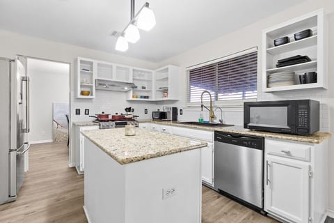 Kitchen with floating open face cabinets, granite counter tops, stainless steel fridge and dish washer and large utilty sink. Additional storage under the kitchen island and large 1000 w microwave.