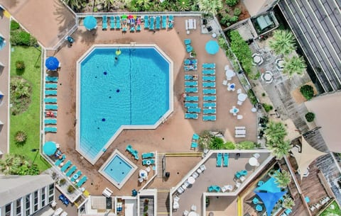 Aerial view of the huge beachfront pool deck with loungers, umbrellas, and a kiddie pool.