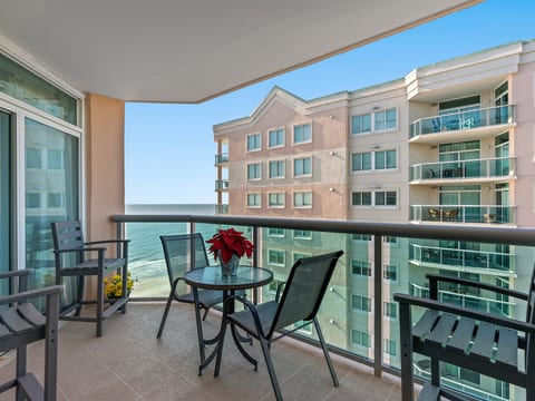 Private balcony with seating, dining table, and partial ocean views
