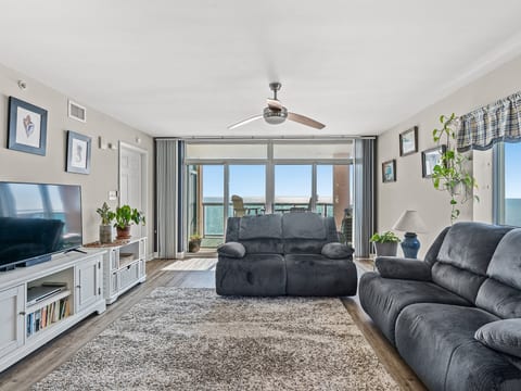 Bright oceanview living room with balcony access and comfy recliners