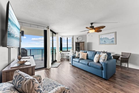 Relax in the airy living room with Gulf-front balcony access and cozy coastal furnishings perfect for family gatherings.