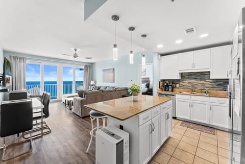 Spacious open-concept kitchen and living room with floor-to-ceiling Gulf views and balcony access for the perfect beach getaway.