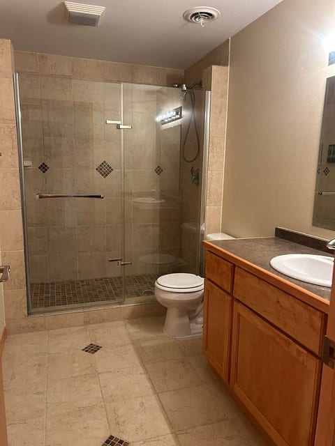 Spacious bath with glass walk-in shower and warm wood vanity