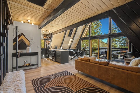 Chic A-frame great room with vaulted ceilings, wall of glass, and forest-view deck.