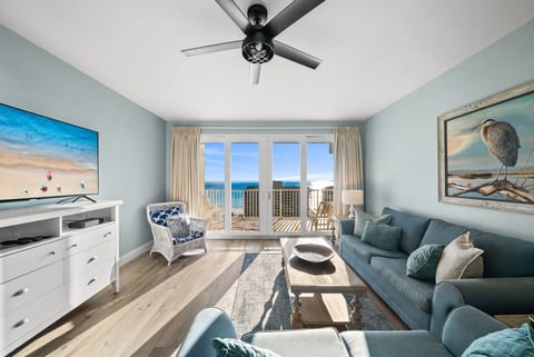 Bright coastal living room with stunning floor-to-ceiling Gulf views and balcony access.