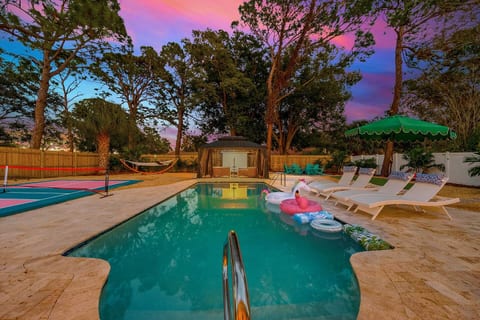 Golden-hour magic in your private resort oasis - heated pool, pickleball court, luxe loungers, outdoor movie theater, hammocks under the stars, and sunset skies. Secluded, elevated, and just 5 minutes from the beach