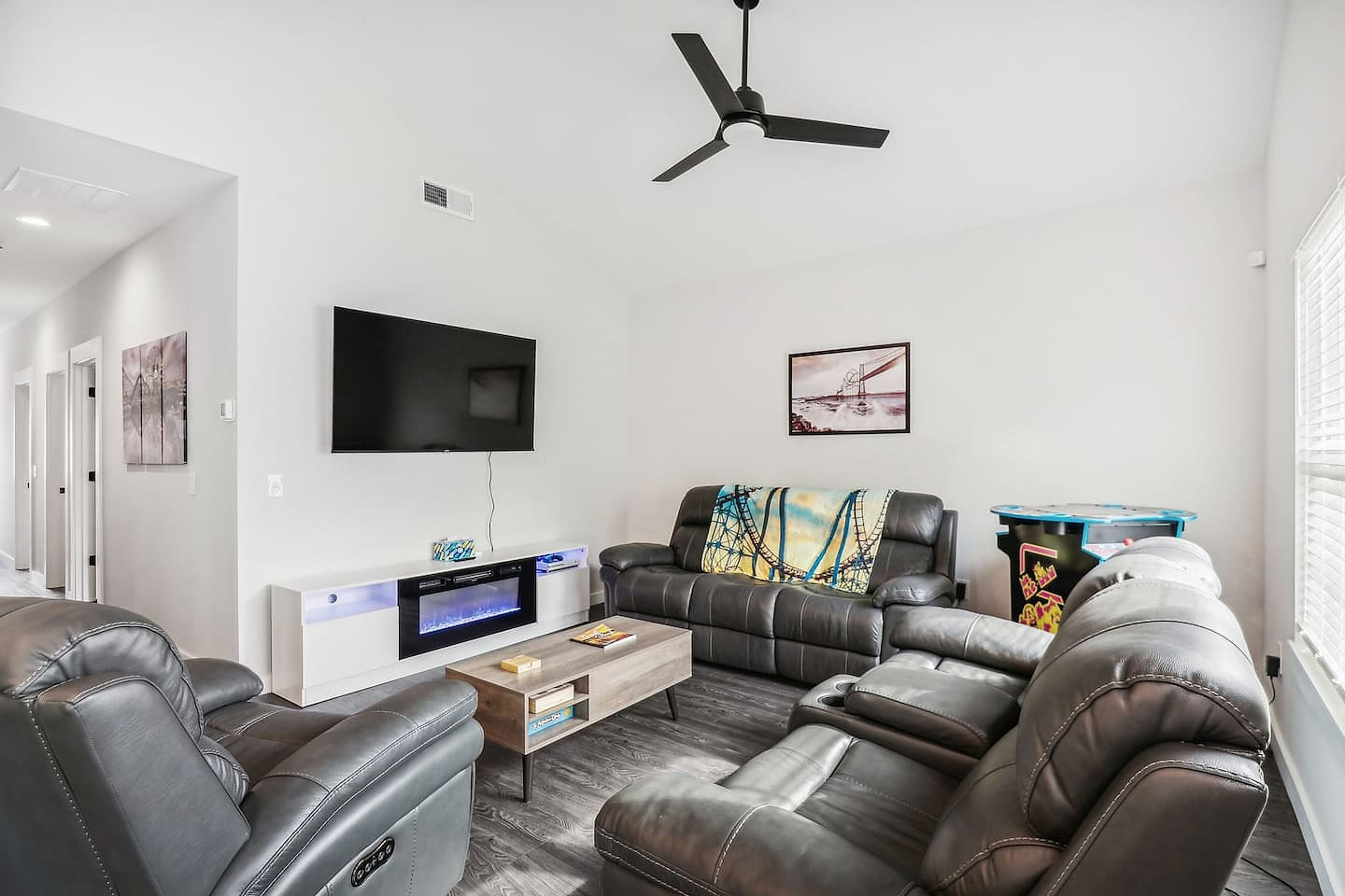Living room with Smart TV with streaming, Xbox 1S with games and Blu-ray, electric fireplace, power reclining couches, lift-up coffee table, and full-size head-to-head Arcade game with Ms. Pacman and 10 other games.