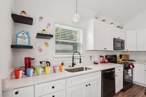Coffee mugs with Keurig coffee maker (pods included), hot water heater, mini waffle maker, blender, stove, oven, dishwasher, fridge, filtered water, knives, cutting board, pots/pans, baking sheets, utensils.