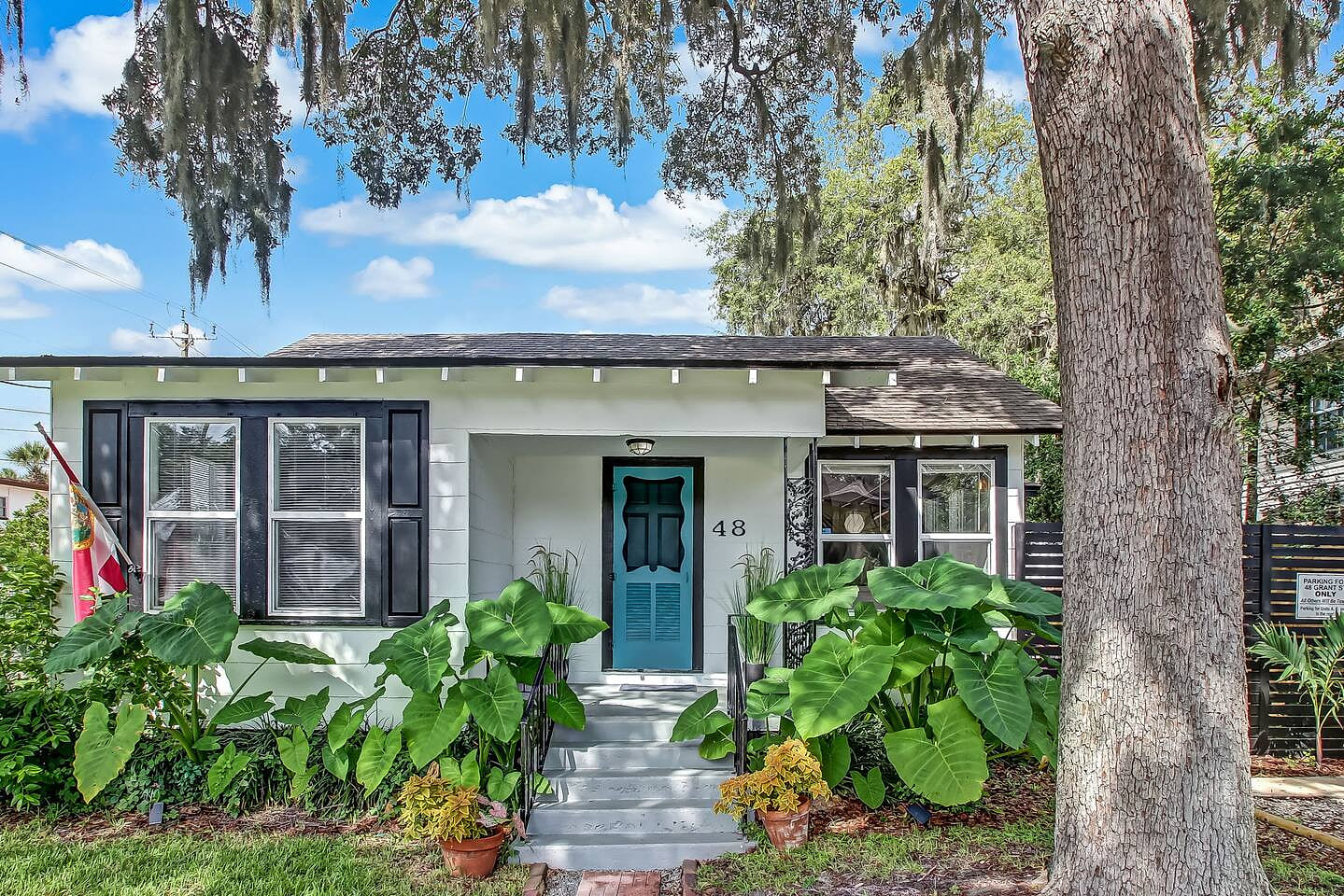 Charming coastal cottage with tropical greenery and a bright teal door; your peaceful Saint Augustine escape begins here.