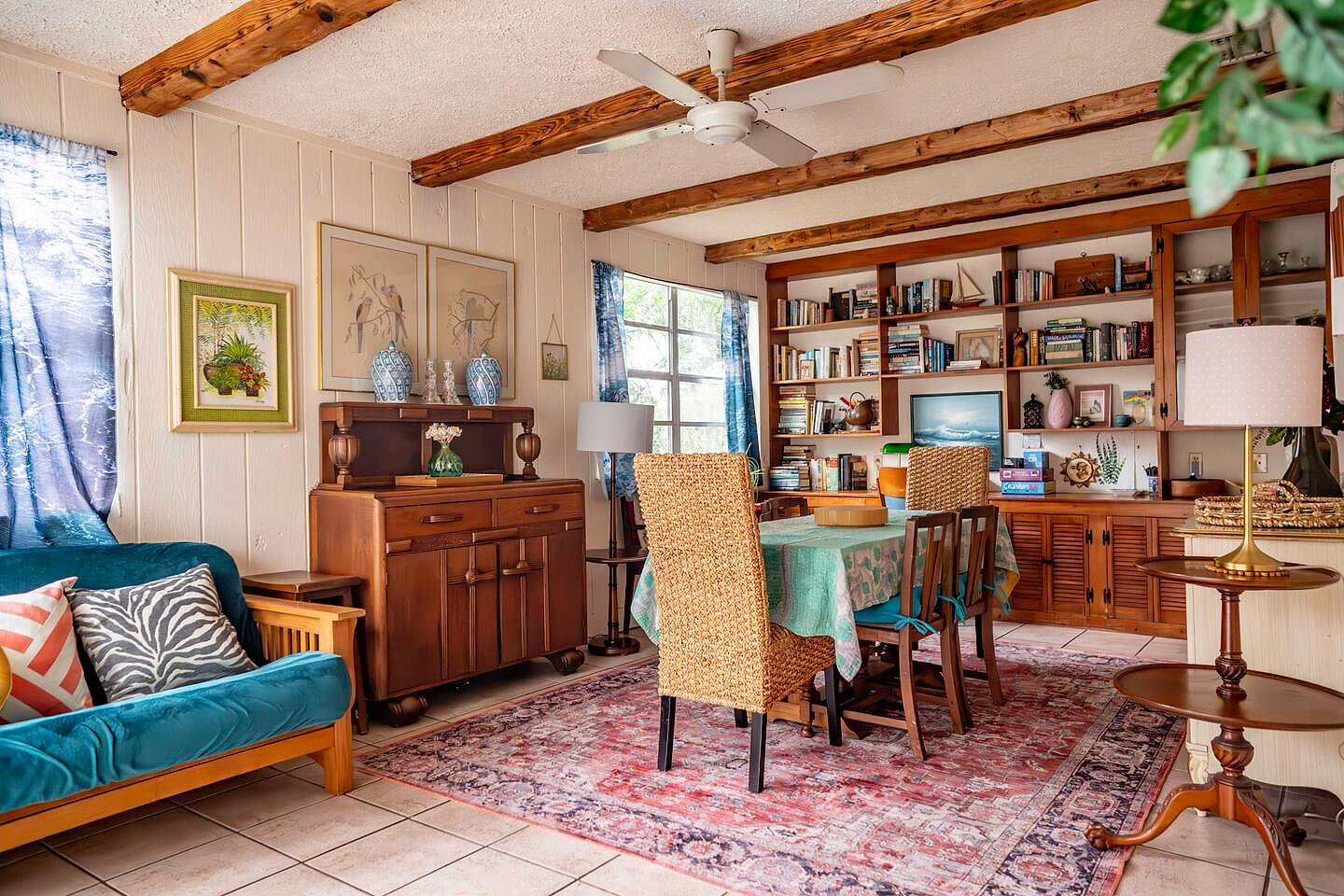 Bright bohemian living + dining space filled with vintage furniture, art, and natural light. Cozy, colorful, and full of personality; perfect for relaxing, reading, or enjoying slow mornings in true old-Florida style.