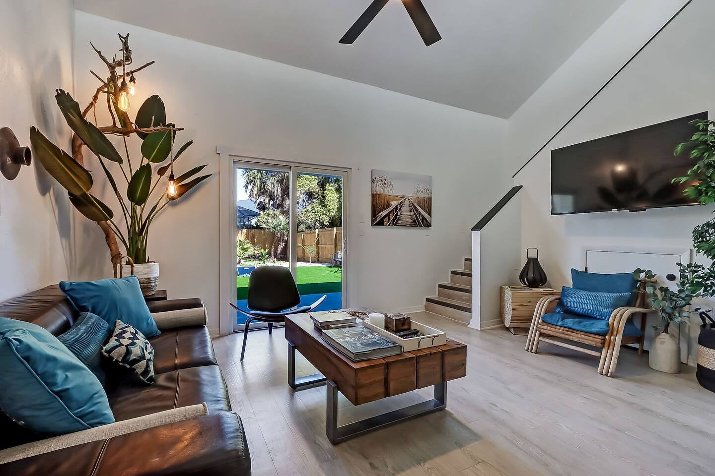 Bright, airy living room with vaulted ceilings and boho touches. Perfect for relaxing after the beach, with easy backyard access and plenty of natural light for a calm coastal vibe.