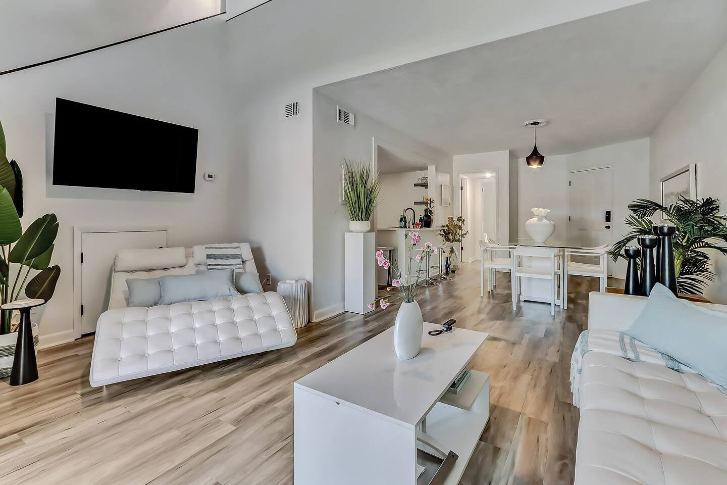 Bright and airy living space with vaulted ceilings, soft coastal tones, and comfy seating. A relaxing spot to unwind after the beach or enjoy time together in a calm, stylish setting.