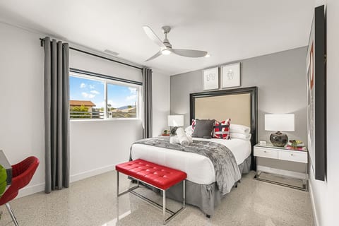 Bright bedroom w/ patterned bedding, ceiling fan & crisp finishes for a comfortable night’s rest