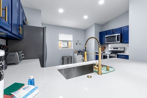 Modern kitchen with stainless appliances, bold blue cabinets, and gold accents - fully equipped for your stay