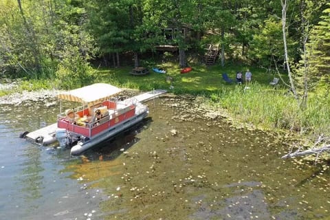 A sweet bird’s-eye peek at your private waterfront paradise, firepit for cozy nights, lush trees for sneaky shade naps, & your charming pontoon boat, ready for little lake adventures. (Old dock in picture)  brand-new dock installed 6/22, even sturdier for making memories.