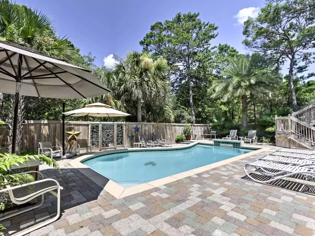 The pool deck is lined with outdoor furnishings and shade umbrellas. - 5 Bd sleeps 14 Heated Pool, Hot Tub & Golf Cart - Santa Rosa Beach