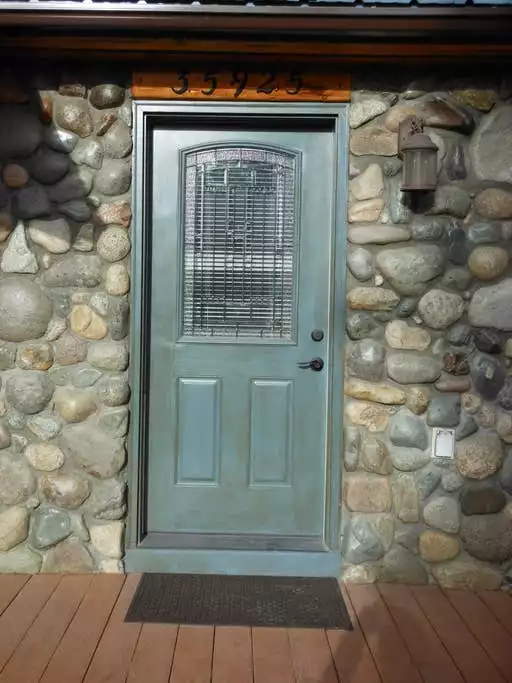 Stone door entry on main house to shared laundry area, wine cooler and garage.