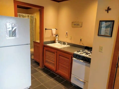 Well lit kitchen with full size refrigerator, supply closet, small stove / oven.