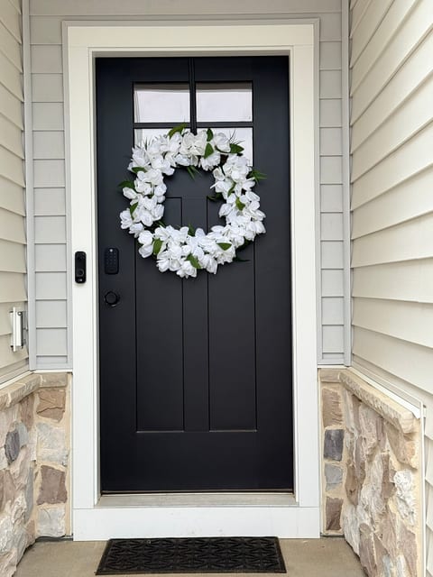 Elegant front entry with modern black door and welcoming floral wreath