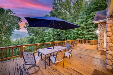 Main floor deck with large dining table, umbrella, rocking chairs, and grill.