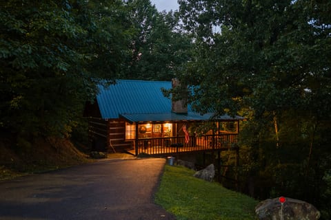 Tucked into the woods on Bluff Mountain, Nestled Oaks glows warmly at dusk — your romantic Smoky Mountain hideaway awaits.