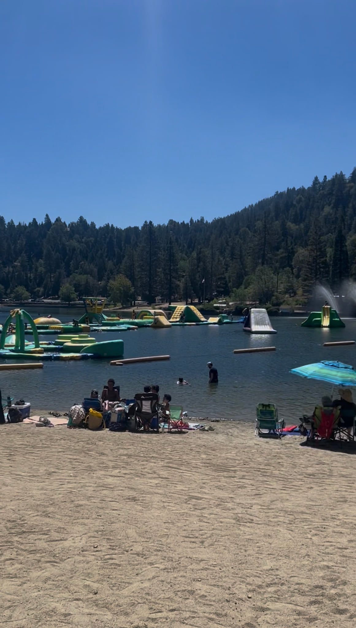 Lakeside beach with inflatable water park and mountain views