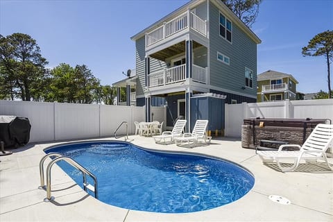 A delightful poolside oasis with a clear view of the house's rear facade.
