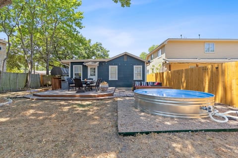 big fenced in backyard with stock tank pool, putting green, outdoor sectional, BBQ, and outdoor dining table