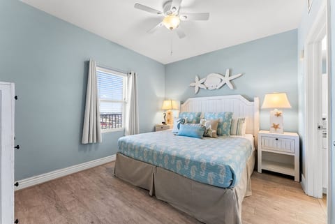 Relax in the serene primary bedroom featuring a plush king bed and calming coastal décor.