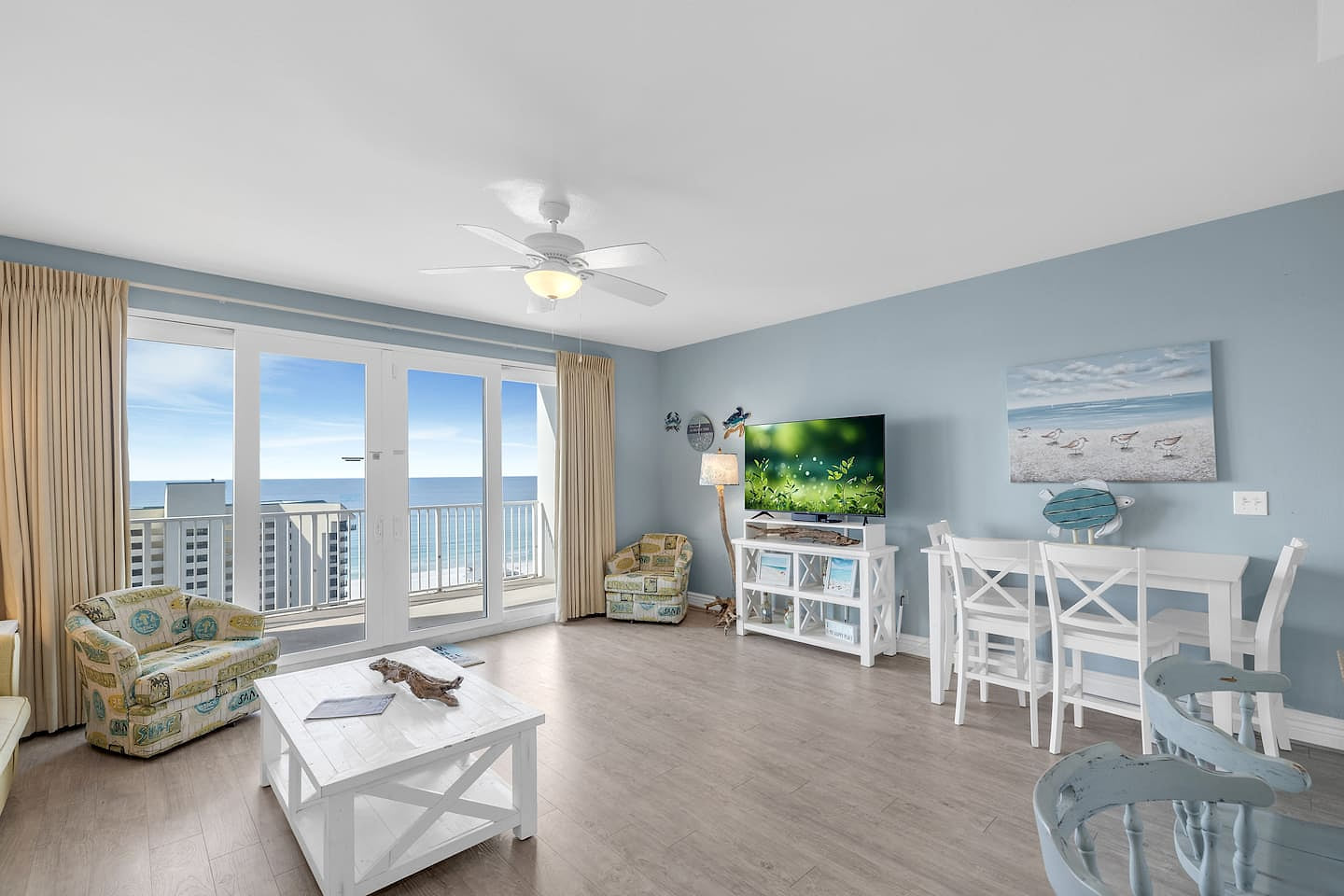 Spacious open-concept living and dining area with Smart TV, ceiling fan, and floor-to-ceiling glass doors.