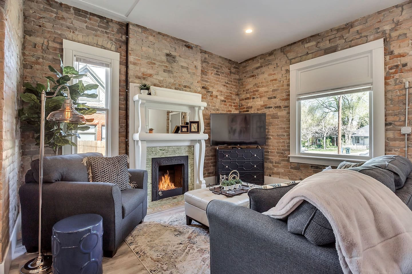 Bright, stylish living space with exposed brick walls, modern décor, and cozy fireplace. Enjoy natural light, smart TV, comfortable seating, and a welcoming layout—perfect for relaxing after exploring the city or working remotely.