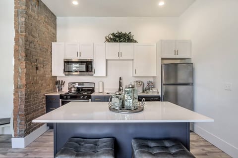 Open concept kitchen with exposed brick, quartz island, stainless steel appliances, and sleek cabinetry. Fully equipped for cooking, dining, or entertaining bright, stylish, and seamlessly connected to the living space for a true loft experience.