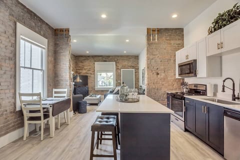 Open concept kitchen with exposed brick, quartz island, stainless steel appliances, and sleek cabinetry. Fully equipped for cooking, dining, or entertaining bright, stylish, and seamlessly connected to the living space for a true loft experience.