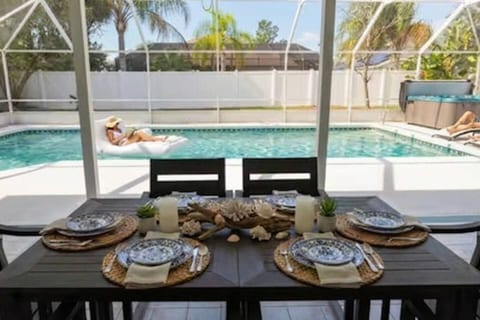 Poolside dining for 6 with heated pool, hot tub & lounge chairs and a outdoor sofa. Florida vacation rental lanai with coastal table settings. Perfect outdoor entertaining near Flagler Beach & St. Augustine attractions.