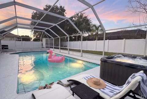 Sunset pool & hot tub with screened lanai, privacy fence & lounge chairs. Florida vacation rental with heated amenities & spacious deck. Perfect evening relaxation near Flagler Beach