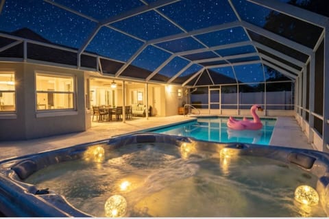 Luxury heated pool & spa under screened lanai at twilight. LED-lit jacuzzi, resort-style amenities. Perfect romantic getaway or family retreat in Palm Coast/St. Augustine area.