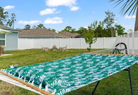 Fenced backyard retreat with hammock and fire pit seating.