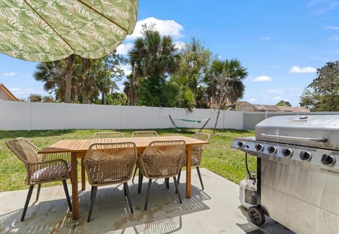 Fenced yard with grill, 6-seat dining, and hammock under palms