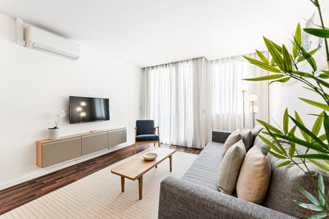 Bright, minimalist lounge with AC, smart TV and floor‑to‑ceiling windows