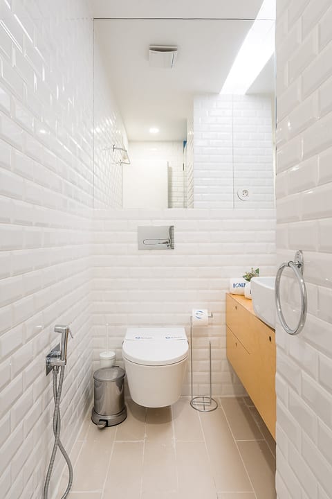 Bright, modern bath with wall-hung toilet, vessel sink, and large mirror.
