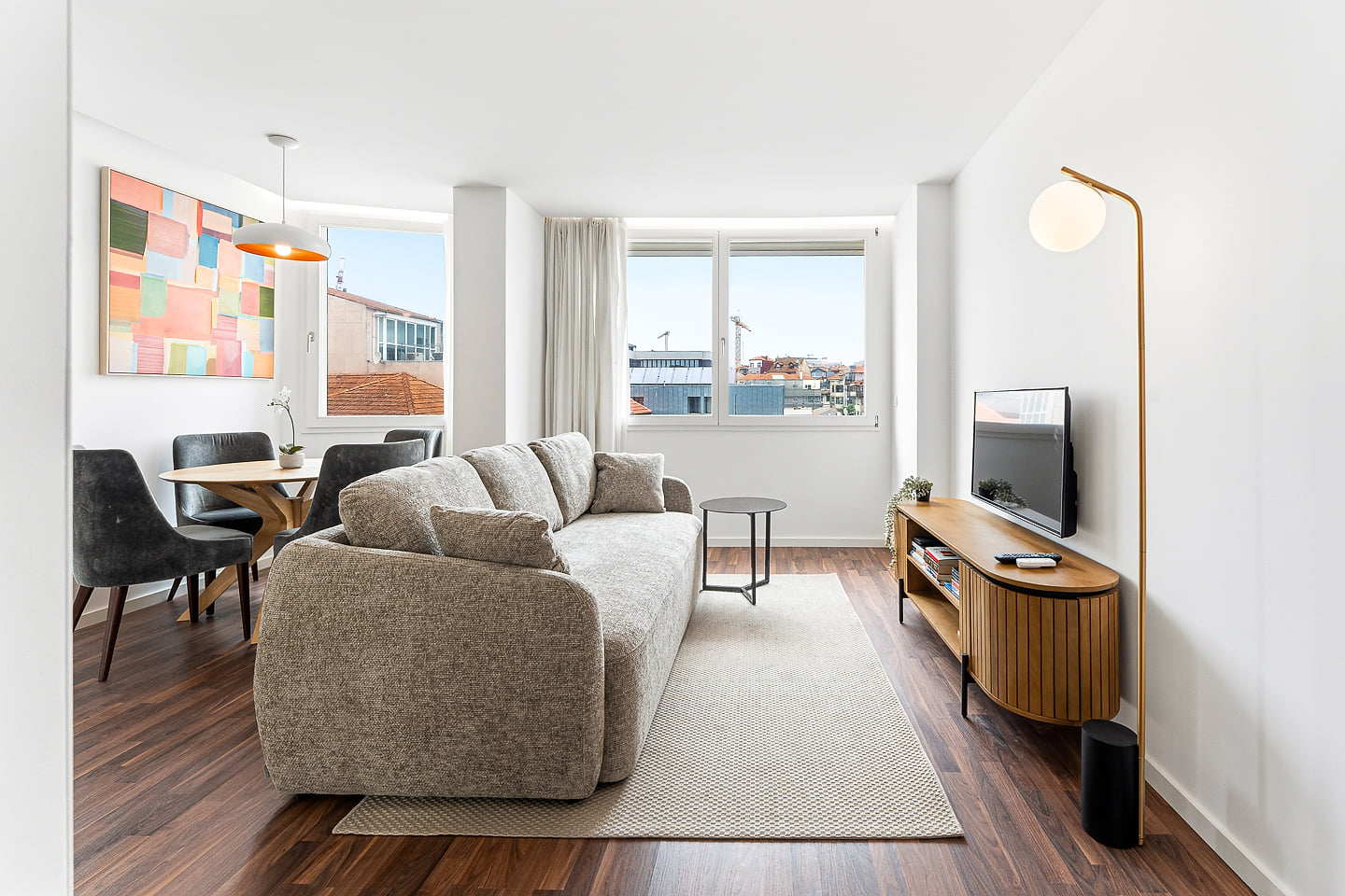 Bright modern lounge with city views, cozy sofa, and stylish dining nook